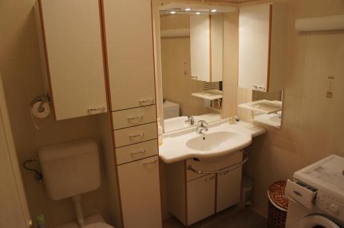 a bathroom with a sink and a toilet and a mirror at Viktória Beach Apartman Gold 2. Siófok in Siófok