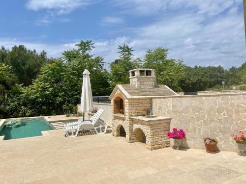 a patio with a stone fireplace next to a swimming pool at V&V Medulin pool and sea in Medulin