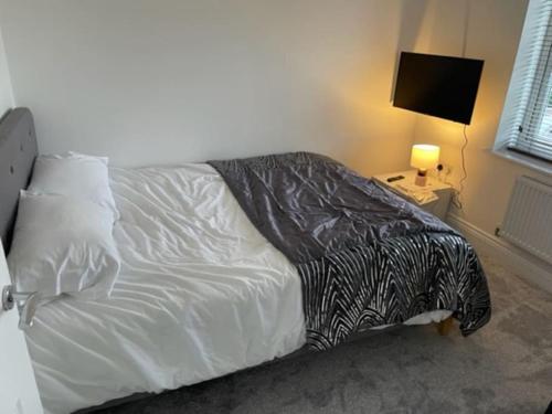 a bed with a black and white blanket on it at *BRAND NEW* renovated 3 bed with parking & WIFI in Corby