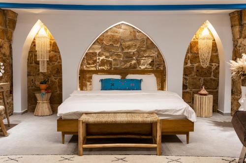 um quarto com uma cama e uma parede de pedra em Santorini em Acre