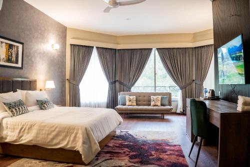 sypialnia z łóżkiem, biurkiem i kanapą w obiekcie Hillside Residence E-7 by Paramount Hospitality w mieście Islamabad