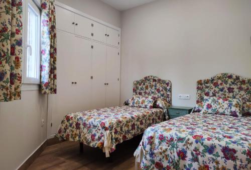 1 dormitorio con 2 camas, silla y ventana en APARTAMENTOS SANLUCAR CASA B, en Sanlúcar de Barrameda
