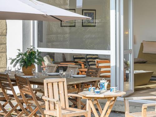 - une table en bois avec des chaises et un parasol sur la terrasse dans l'établissement Apartment La Voilerie - La Brigantine by Interhome, à Carnac