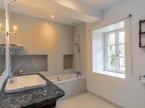 La salle de bains est pourvue d'un lavabo, d'une baignoire et d'une fenêtre. dans l'établissement Apartment Zenaïde by Interhome, à Concarneau