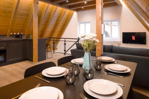 a dining room table with white plates and flowers on it at Stadtmauer-Apartments - Großzügige luxuriöse Wohnung direkt an der historischen Stadtmauer ideal für Familien in Nördlingen