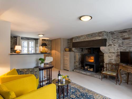 een woonkamer met een gele bank en een open haard bij Apartment Le Manoir du Moros by Interhome in Concarneau
