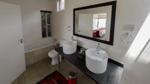 a bathroom with two sinks and a toilet and a mirror at Orangerie Guest House in Johannesburg