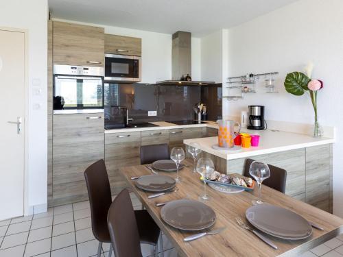 - une cuisine avec une table en bois, des assiettes et des verres à vin dans l'établissement Apartment La Baie des Corsaires-8 by Interhome, à Saint-Malo