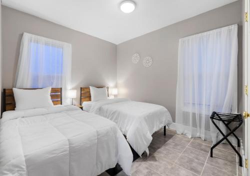 una camera bianca con due letti e una finestra di Vida Comfy Inn 3 bedroom Apartment 8 mins to downtown and ferry a New Bedford