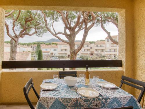 stół z butelką wina i okno z drzewami w obiekcie Apartment L'Ile heureuse-7 by Interhome w mieście Saint-Cyr-sur-Mer