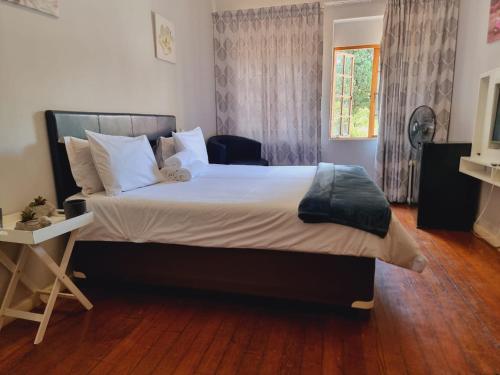 een slaapkamer met een groot bed en een houten vloer bij Houghton Skye in Johannesburg