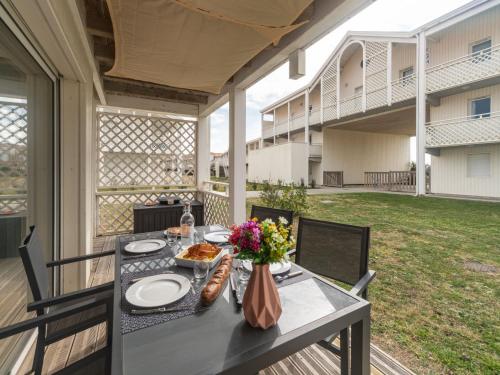 - une table avec de la nourriture et des fleurs sur la terrasse dans l'établissement Apartment Les balcons des pêcheurs C21 by Interhome, à Mimizan