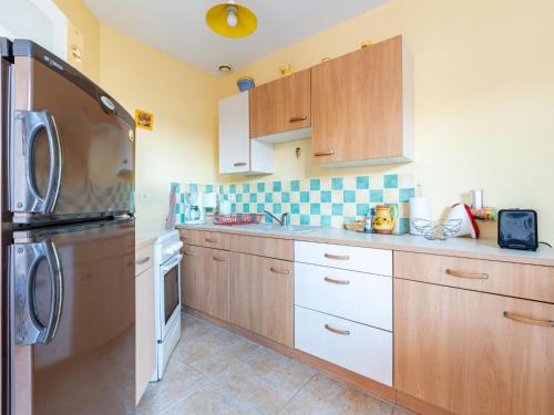 une cuisine avec des armoires en bois et un réfrigérateur dans l'établissement Holiday Home L'Abrivado by Interhome, à Aigues-Mortes