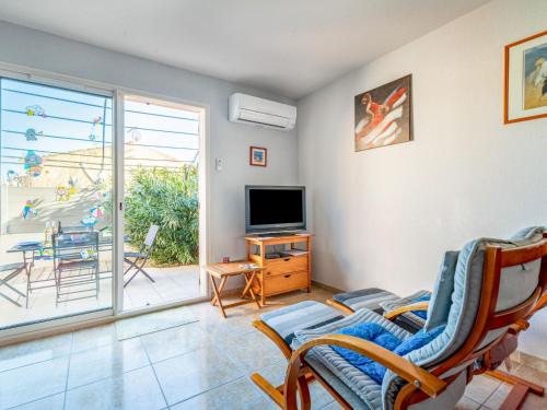 - un salon avec une télévision et une porte coulissante en verre dans l'établissement Holiday Home L'Abrivado by Interhome, à Aigues-Mortes