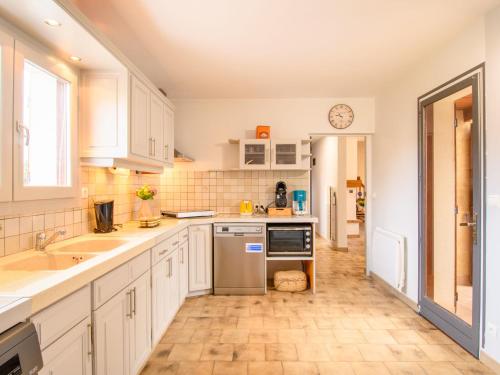 a kitchen with white cabinets and a clock on the wall at Holiday Home Yuvita by Interhome in Mimizan