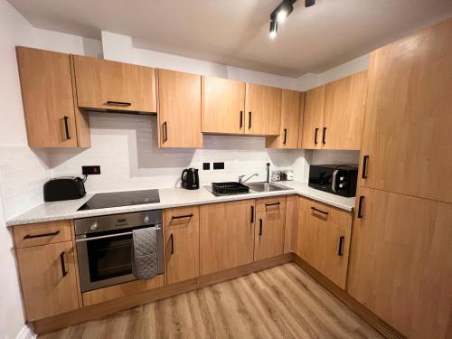 a kitchen with wooden cabinets and a sink and a stove at Cosy 2 Bed Apartment Minutes From Bournemouth Beach & Town in Bournemouth