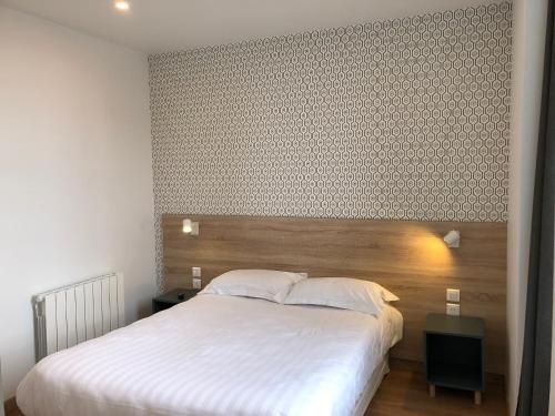 a bedroom with a large bed with a wooden headboard at Hôtel Océan Dinan in Dinan