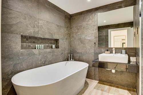 y baño con bañera blanca y lavamanos. en Bright stylish sea view apartment in JBR, en Dubái