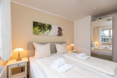 een slaapkamer met een groot wit bed en 2 witte handdoeken bij Hafendorf Haus 7_ Apartment 4 in Plau am See