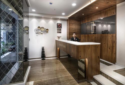 a man standing at a reception desk in a lobby at Hotel Royal Treat Surat in Surat