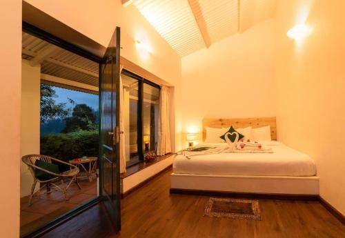 een slaapkamer met een bed en een groot raam bij The Tamarillo in Ooty