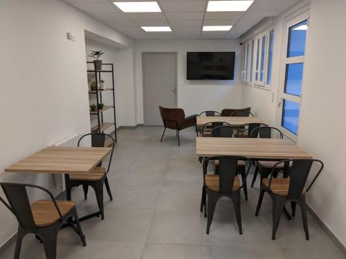 une salle d'attente avec des tables, des chaises et une télévision dans l'établissement Hôtel Océan Dinan, à Dinan