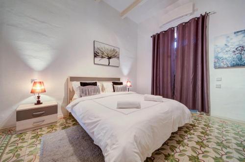 a bedroom with a large white bed and a window at Valletta 2 bedroom sleeps 6 apartment walking distance to centre and the sea in Valletta