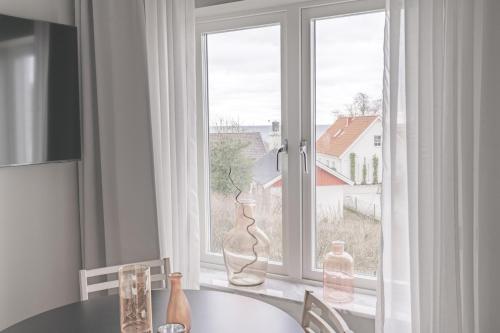 a dining room table with vases sitting in front of a window at Hotell Hanöhus Hällevik in Sölvesborg