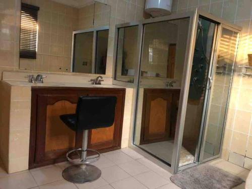 La salle de bains est pourvue d'une douche et d'une chaise noire. dans l'établissement 3 bdr pool house near Brusubi and brufut Heights, à Brufut
