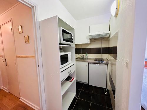 une petite cuisine avec des armoires blanches et un évier dans l'établissement Résidence l'Hermitage - appart face aux thermes, à Royat