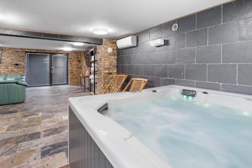 a large bath tub in a room with a brick wall at Willa pod Warszawą & SPA & Grota Solna in Rybie