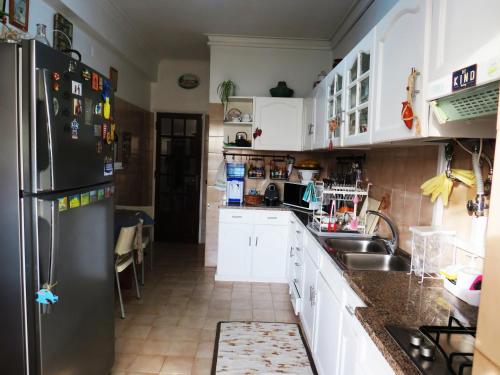 a kitchen with white cabinets and a black refrigerator at Al-Madan in Almada
