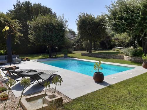 uma piscina num quintal com cadeiras e árvores em Le Patio 4*. SPA, jardin, piscine en provence, proche Grignan em Saint-Paul-Trois-Châteaux