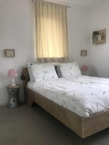 a bedroom with a bed with white sheets and a window at B&B Achterhoeks Halle in Halle