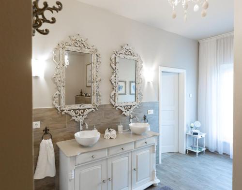 a bathroom with two sinks and mirrors on the wall at Gästehaus Landglück in Langen