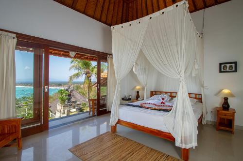 a bedroom with a canopy bed with a view of the ocean at Lembongan Cliff Villas in Nusa Lembongan