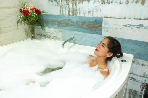 a woman sitting in a bath tub with a vase of flowers at Auka Boutique San Blas in Cusco