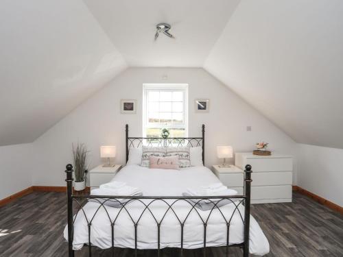 a bedroom with a bed with white walls and a window at Cwt Ci in Llangefni