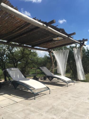 two lounge chairs under a pergola on a patio at Color Local Cabañas in San Javier