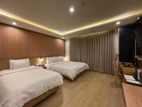 釜山的住宿－Hotel Prima Busan，酒店客房设有两张床、一张桌子和一台电视。