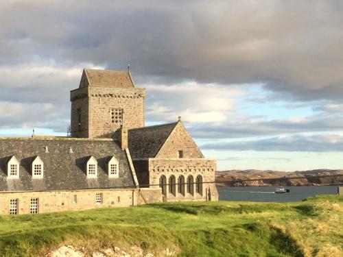 une vieille église sur une colline avec une masse d'eau dans l'établissement Martyrs Bay Rooms, à Iona