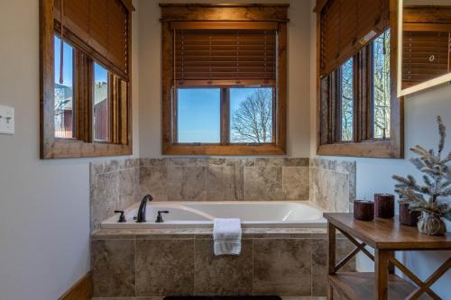 ein Badezimmer mit einer Badewanne und zwei Fenstern in der Unterkunft Little Cubs Cabin at Eagles Nest in Banner Elk