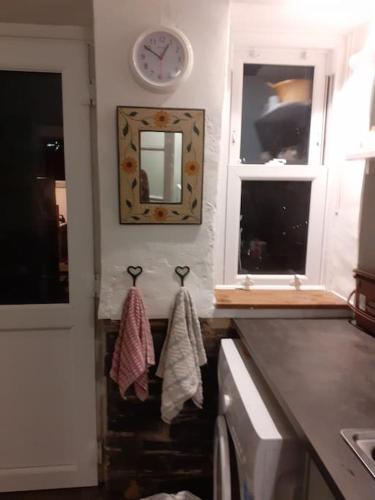 a kitchen with a sink and a clock and towels at Welcome to Robert’s Cottage. in Abergynolwyn