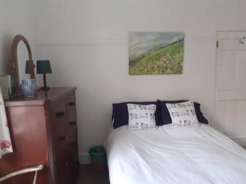 a bedroom with a bed and a painting on the wall at Welcome to Robert’s Cottage. in Abergynolwyn