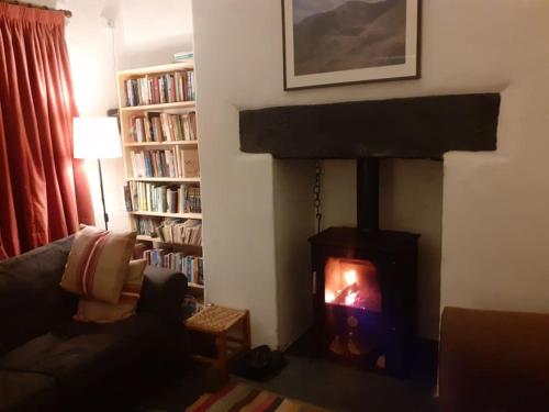 a living room with a fireplace with a fire in it at Welcome to Robert’s Cottage. in Abergynolwyn