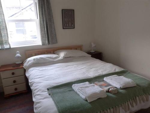 a bedroom with a bed with towels on it at Welcome to Robert’s Cottage. in Abergynolwyn