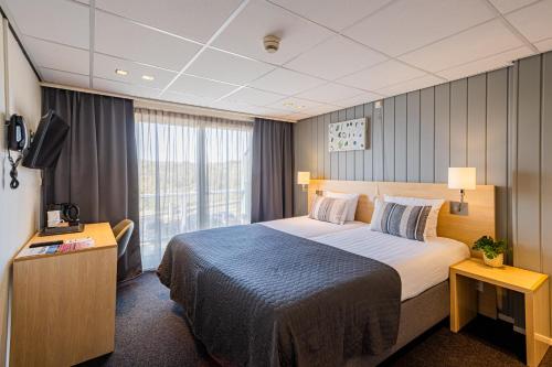 a hotel room with a large bed and a television at Hotel De Boei in Egmond aan Zee