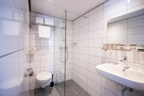 La salle de bains est pourvue de toilettes, d'un lavabo et d'une douche. dans l'établissement Hotel De Boei, à Egmond aan Zee