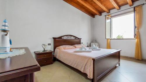 a bedroom with a bed with a table and a window at Casetta Orchidea A pochi passi dal Centro in Lampedusa