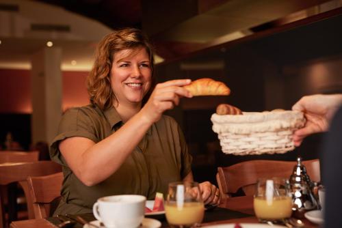 a woman sitting at a table holding a piece of bread at Goldener Schlüssel in Bern